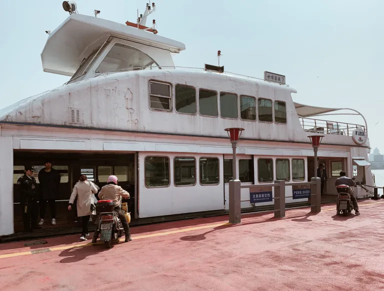 Passengers boarding a ferry with scooters on the Shanghai waterfront