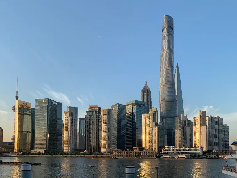Shanghai towers reflecting evening light across the river