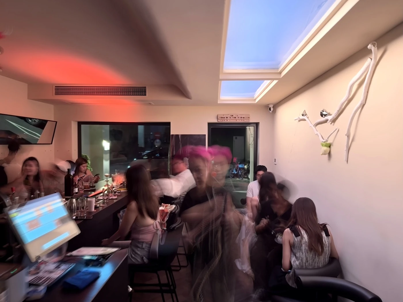 Crowded Good Afternoon Bar interior with motion blur beneath red and blue artificial skylights