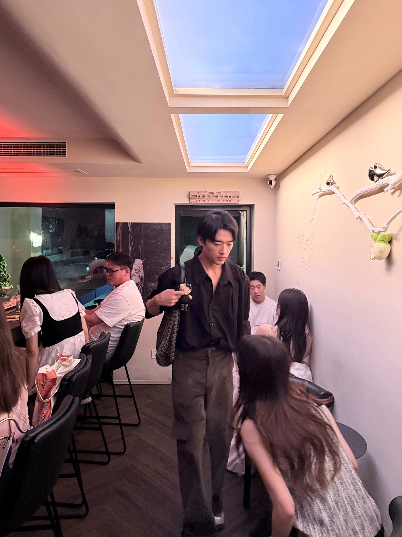 Busy opening-night interior beneath blue artificial skylights